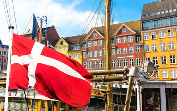 Denmark&#39;s national flag flying in the foreground of Copenhagen&#39;s famous old Nyhavn port.