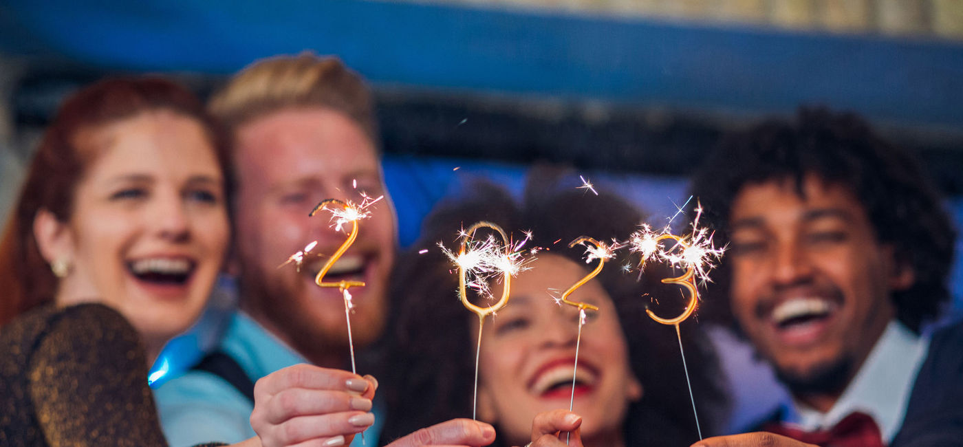 Image: Friends celebrating 2023's arrival with some sparklers. (photo via iStock/E+/RgStudio)