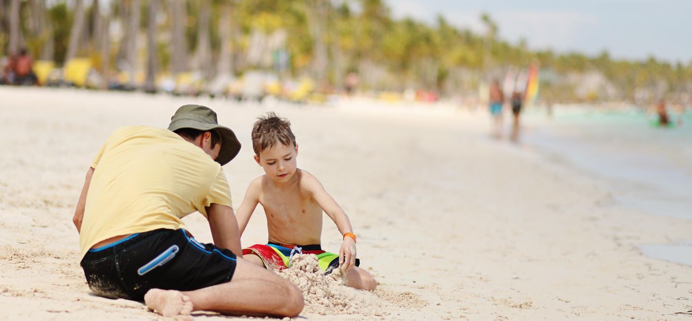 Image: PHOTO: Father and son playing in the sand in Punta Cana, Dominican Republic. (photo via mayakova/iStock/Getty Images Plus)