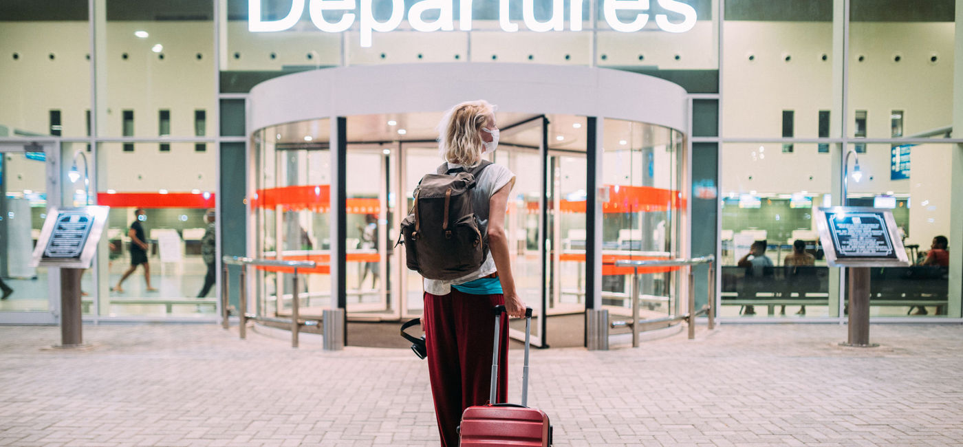Photo: Young woman heading toward her departure gate at the airport. (photo via iStock/Getty Images E+/Pyrosky)