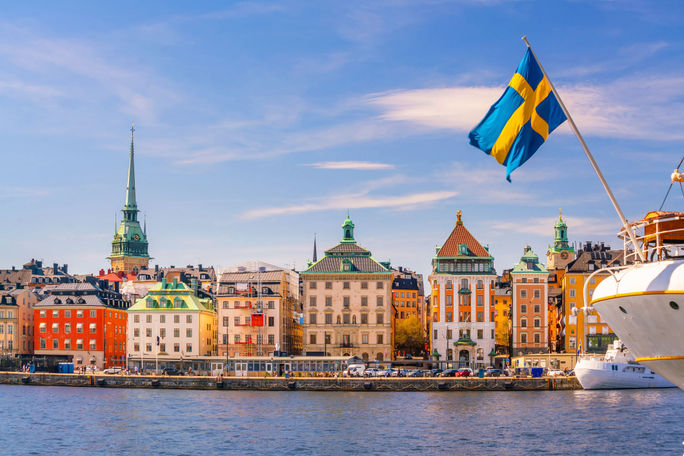 Waterfront in Old Town Stockholm with the Swedish national flag in the foreground. Old town, waterfront, cruise ship, Stockholm, Sweden, flag