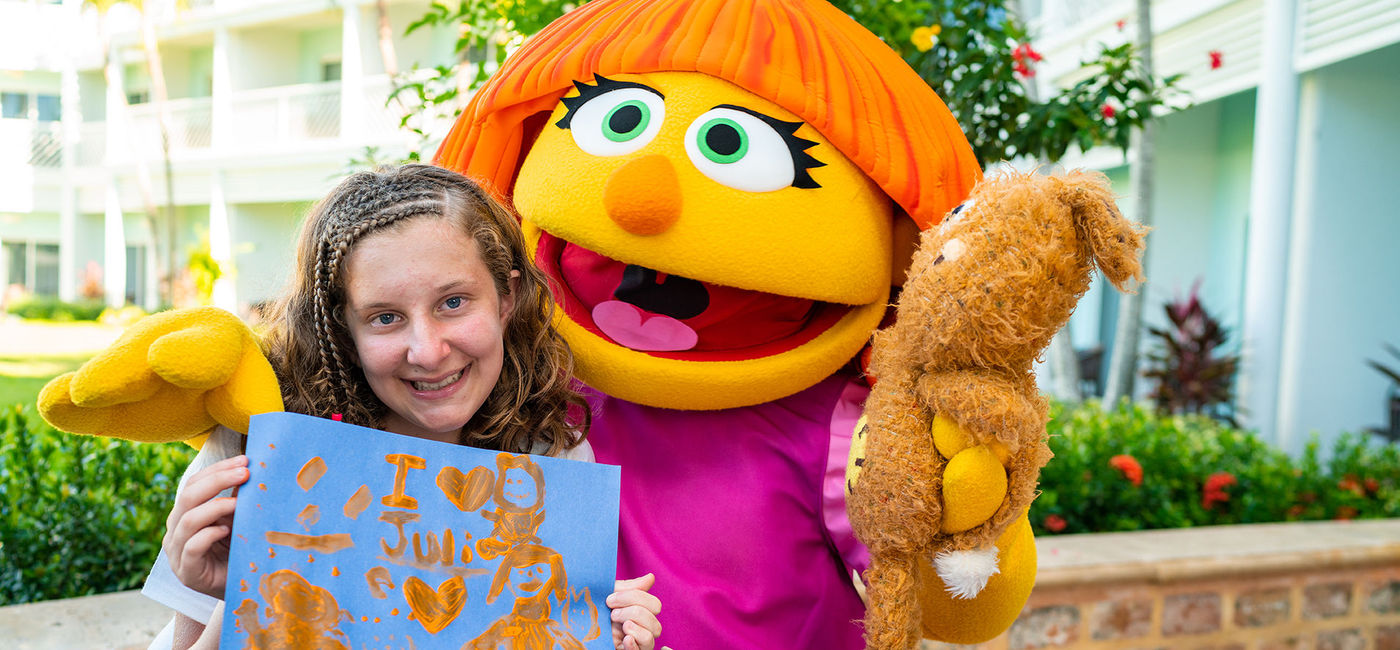 Image: A child poses for a picture with Julia, the Sesame Street character who has autism, during the Amazing Art with Julia program. (photo via Beaches Resorts) ((photo via Beaches Resorts))