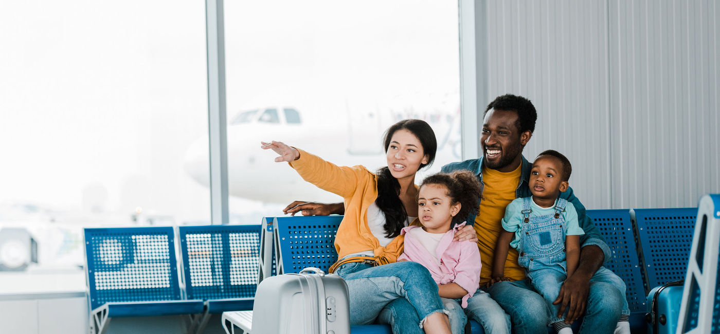 Image: A family sits together at the airport. (photo via  LightFieldStudios / iStock / Getty Images Plus)