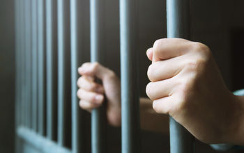 Man in prison behind steel bars.