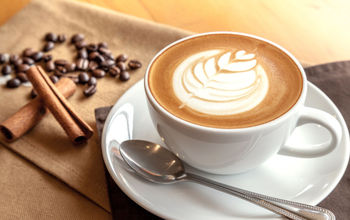 Cafe latte with coffee beans and cinnamon sticks.