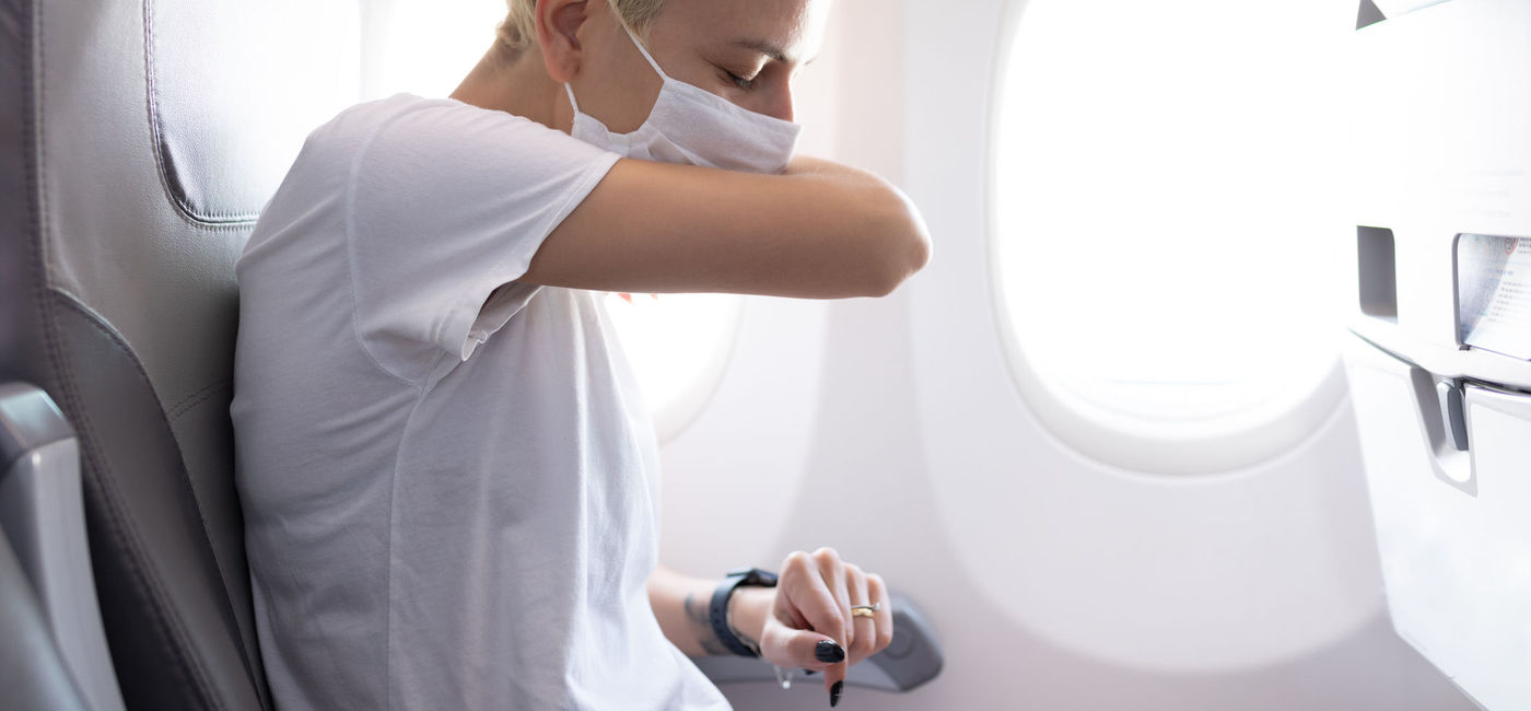 Image: Woman covers a sneeze on an airplane. (photo via merteren/E+)