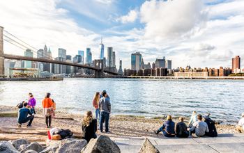 People enjoying the New York City skyline from the Pebble Beach shore