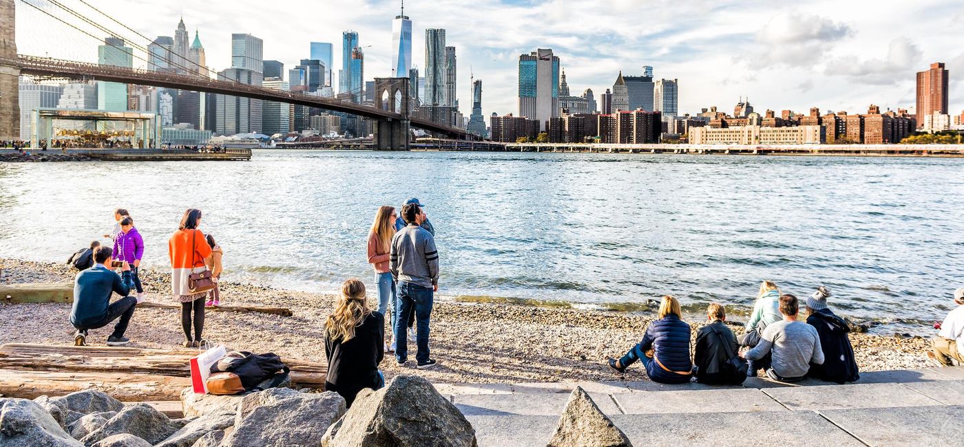 Image: Visitors enjoying the New York City skyline from the Pebble Beach shore. (photo via ablokhin/iStock Editorial/Getty Images Plus)