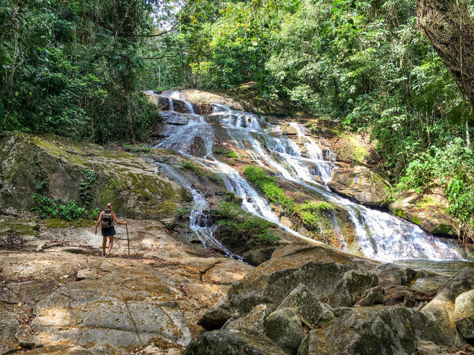 A woman hikes near a waterfall in Belize's Bocawina National Park. Belize, Bocawina National Park, rainforest, Central America, Eco-friendly travel, waterfall