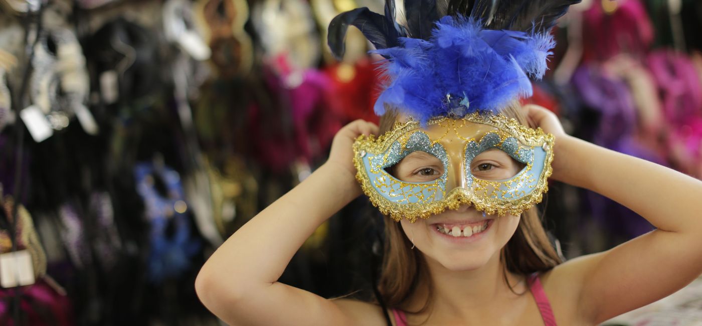 Image: A child tries on a Mardi Gras mask in New Orleans. (photo by Chris Granger via New Orleans & Company) ((photo via New Orleans & Co. / Chris Granger))
