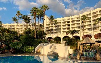 White resort hotel Fairmont Kea Lani during sunset with view of blue resort pool.