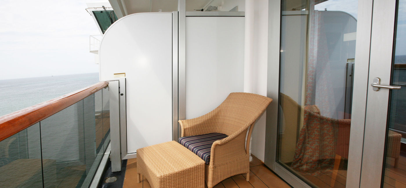 Image: Single chair on solo stateroom balcony. (Photo Credit: Terraxplorer / iStock / Getty Images Plus)