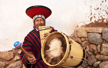 Peruvian man playing a pan flute and drums.