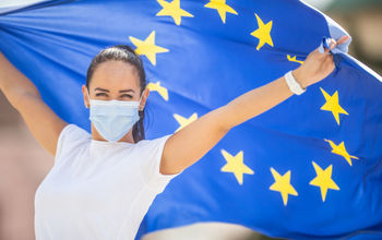 Woman wearing a face mask and flying an E.U. flag.