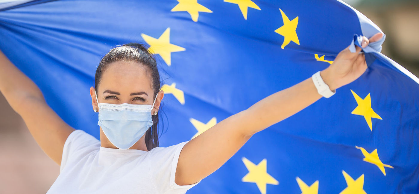 Image: Woman wearing a face mask and flying an E.U. flag. (Photo via iStock/Getty Images Plus/MarianVejcik)