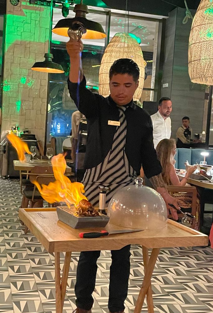A chef attendant flambes lobster with cacha?a A chef attendant flambes lobster with cacha?a