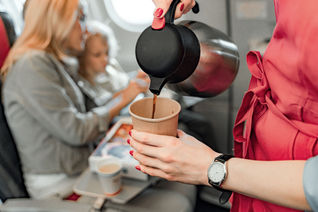 Flight attendant serving coffee mid-flight