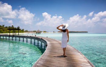 Woman walking along a wooden jetty in the Maldives.