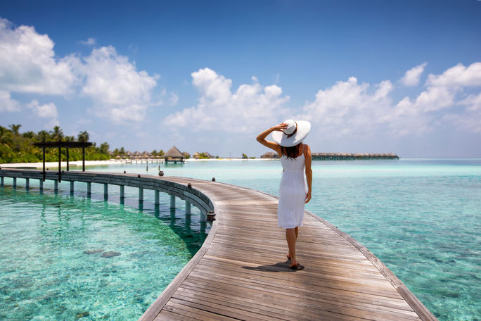 Woman walking along a wooden jetty in the Maldives. Woman walking along a wooden jetty in the Maldives.