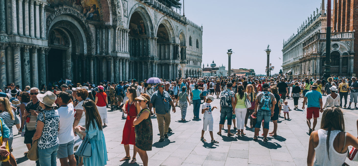 Image: Crowds of travelers in St. Mark's Square, Venice, Italy (Photo Credit: iStock/ Getty Images Plus/ bluebeat76)