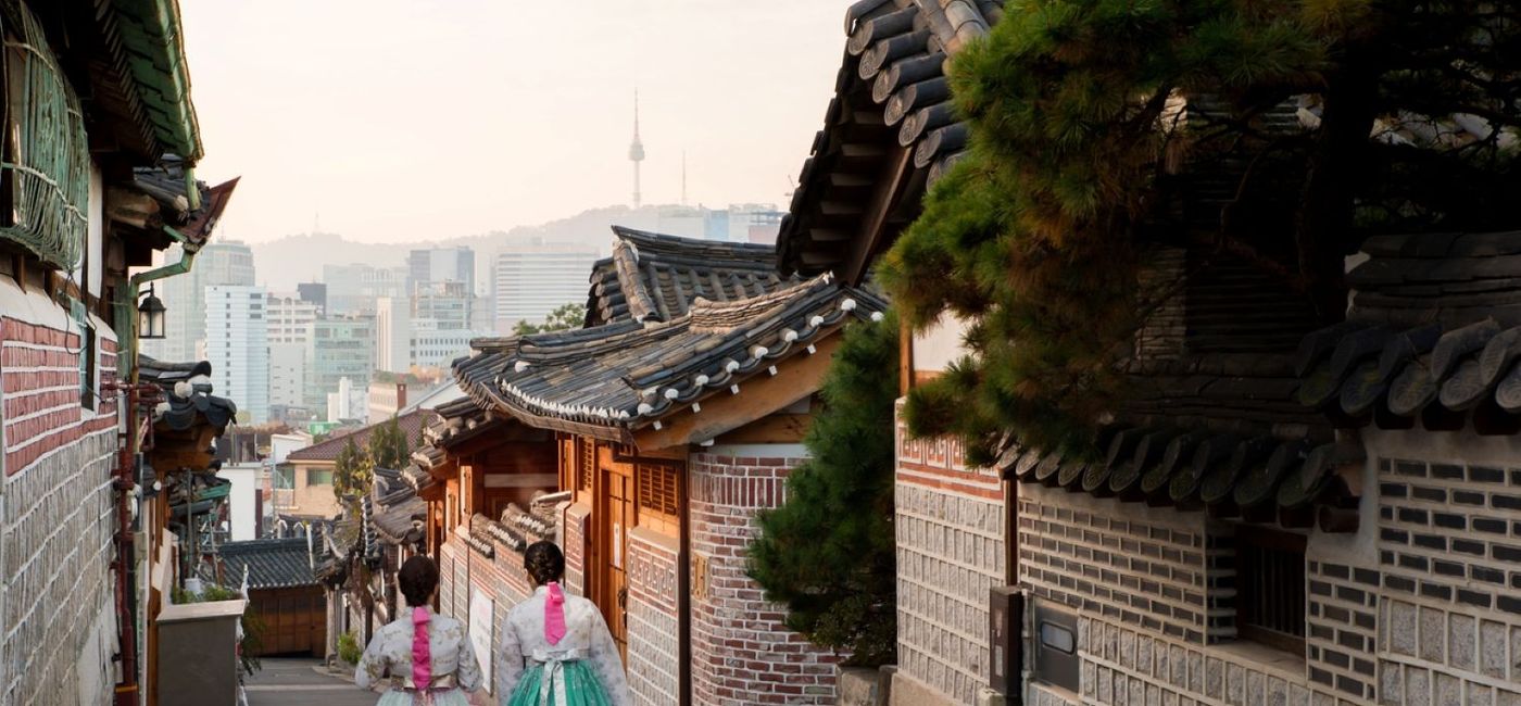 Image: Two women wearing traditional Korean hanboks walk down a street in Seoul's Bukchon Hanok village. (photo via InsideAsia Tours) ((photo via InsideAsia Tours))
