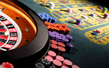 Gambling chips stacked around roulette wheel on gaming table