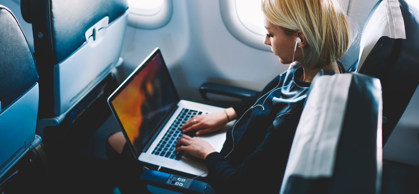 Image: Woman using wi-fi during plane flight. (photo via GaudiLab / iStock / Getty Images Plus)