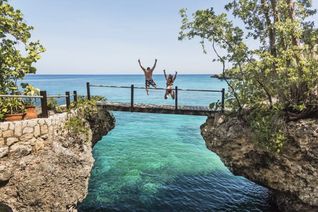 A couple jumping off a bridge into the ocean in Jamaica