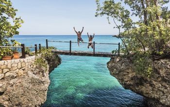 A couple jumping off a bridge into the ocean in Jamaica