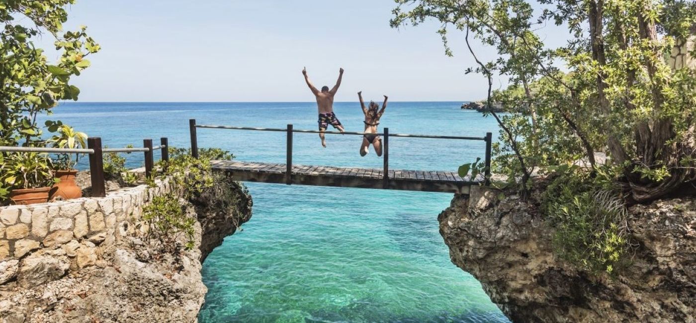 Image: A couple jumping off a bridge into the ocean in Jamaica (photo via ALG Vacations) (Photo Credit: (photo via ALG Vacations))