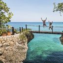 A couple jumping off a bridge into the ocean in Jamaica