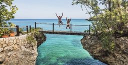 A couple jumping off a bridge into the ocean in Jamaica