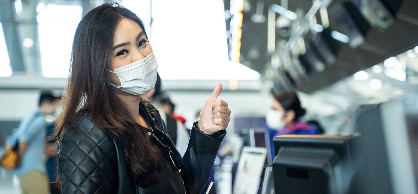Image: Young woman wearing a mask at airport check-in. (Photo via iStock/Getty Images Plus/Kiwis)