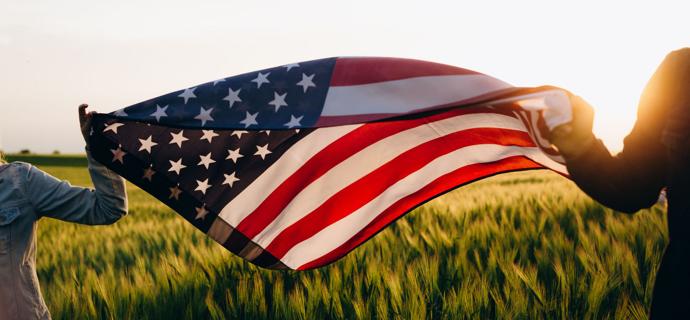 Image: Hands holding American flag in a wheat field on Independence Day. (photo via Galeanu Mihai / iStock / Getty Images Plus)
