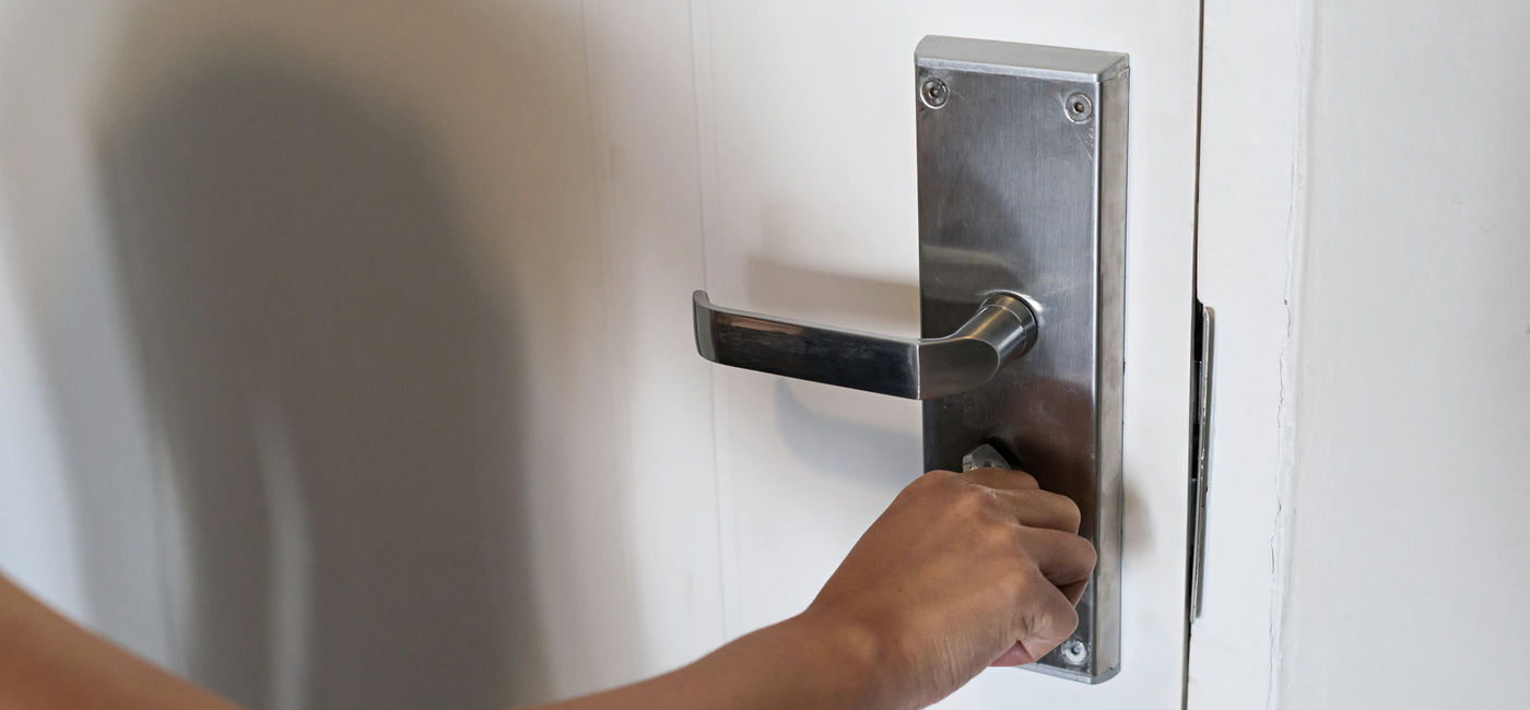 Image: Woman locks the bolt on her hotel door. (photo via  iStock / Getty Images Plus / Oppdowngalon)