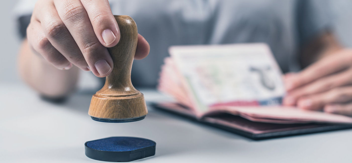 Image: PHOTO: Customs and Immigration Control officer stamping a passport. (Photo via iStock/Getty Images Plus/FTiare)