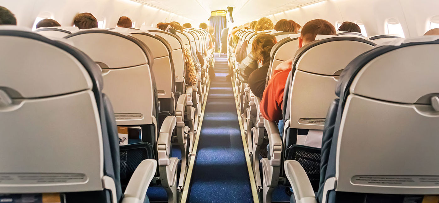 Image: Commercial aircraft cabin with rows of seats down the aisle. (Photo via Diy13 / iStock / Getty Images Plus)