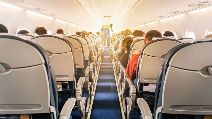 Commercial aircraft cabin with rows of seats down the aisle Commercial aircraft cabin with rows of seats down the aisle (Photo via Diy13 / iStock / Getty Images Plus)