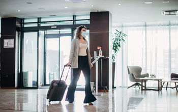 Woman with medical mask arriving in hotel.