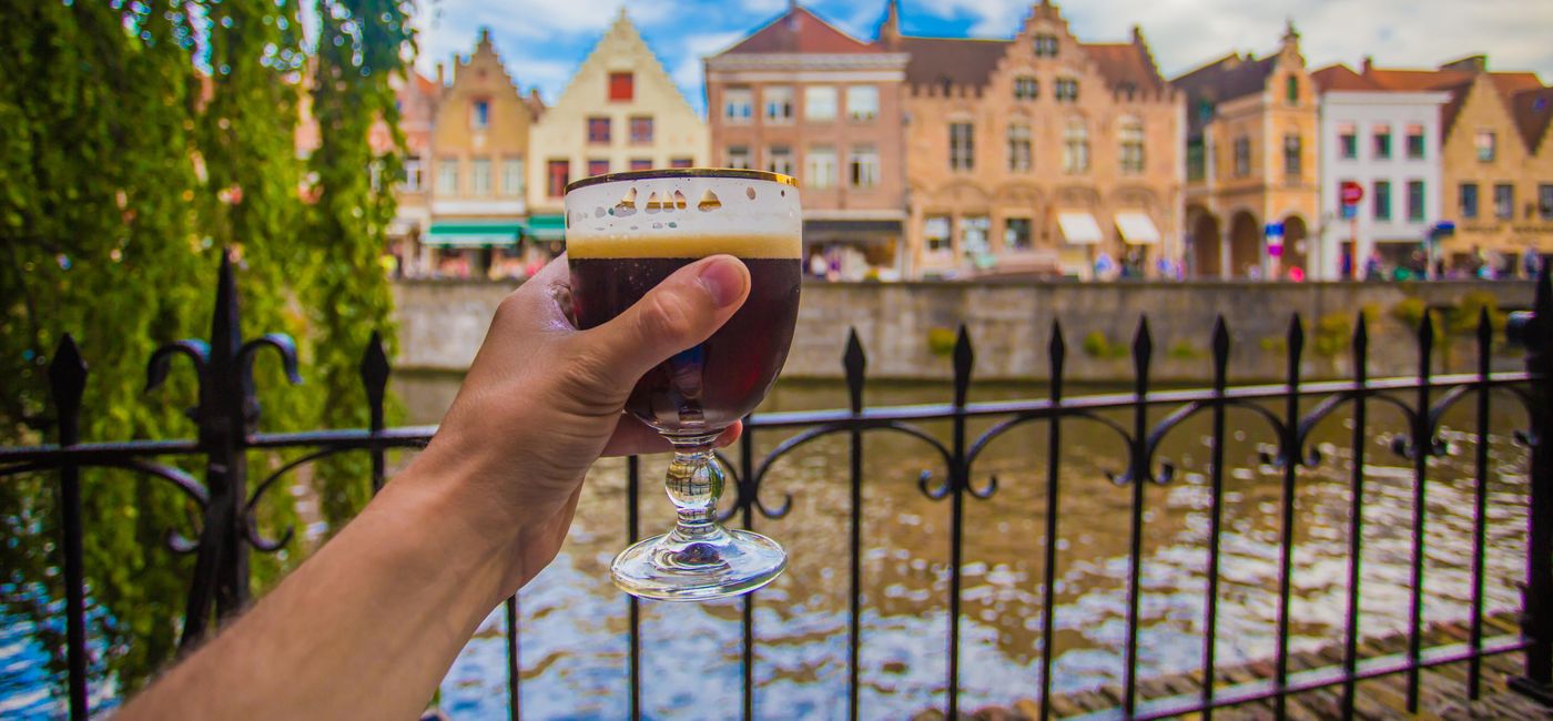 Photo: Hand holding a glass of beer in Bruges, Belgium. (photo via dimarik/iStock/Getty Images Plus)