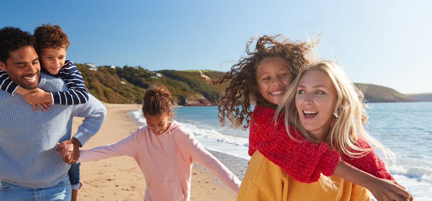 Image: Family having fun on the beach together (photo via monkeybusinessimages / iStock / Getty Images Plus)