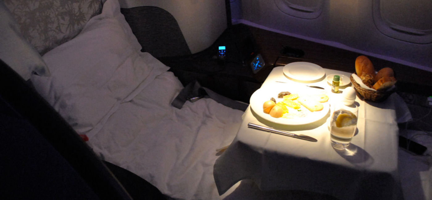 Image: PHOTO: Dinner in Cathay Pacific's First Class cabin. The seat is in bed position, the tray table is out and caviar is being served. (Photo via Tom Mascardo / flickr)