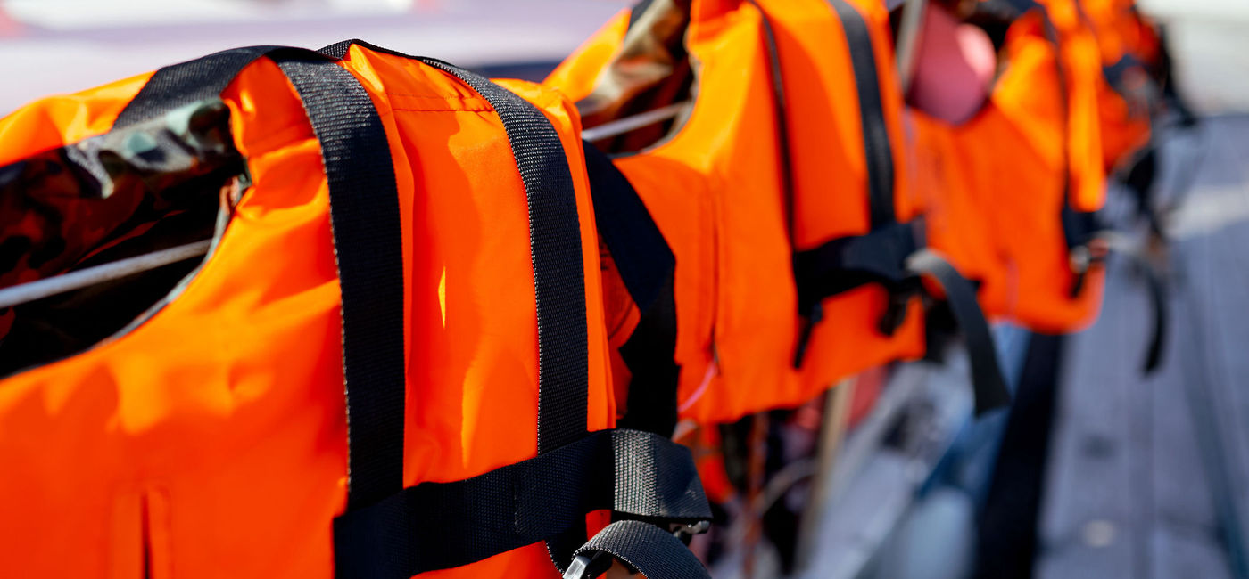 Image: Life jackets laid out on a railing in traditional muster drill style. (photo via iStock/Getty Images Plus/Anton Ilchanka)