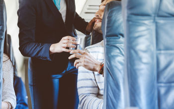 Airline hostess serving water to a passenger.