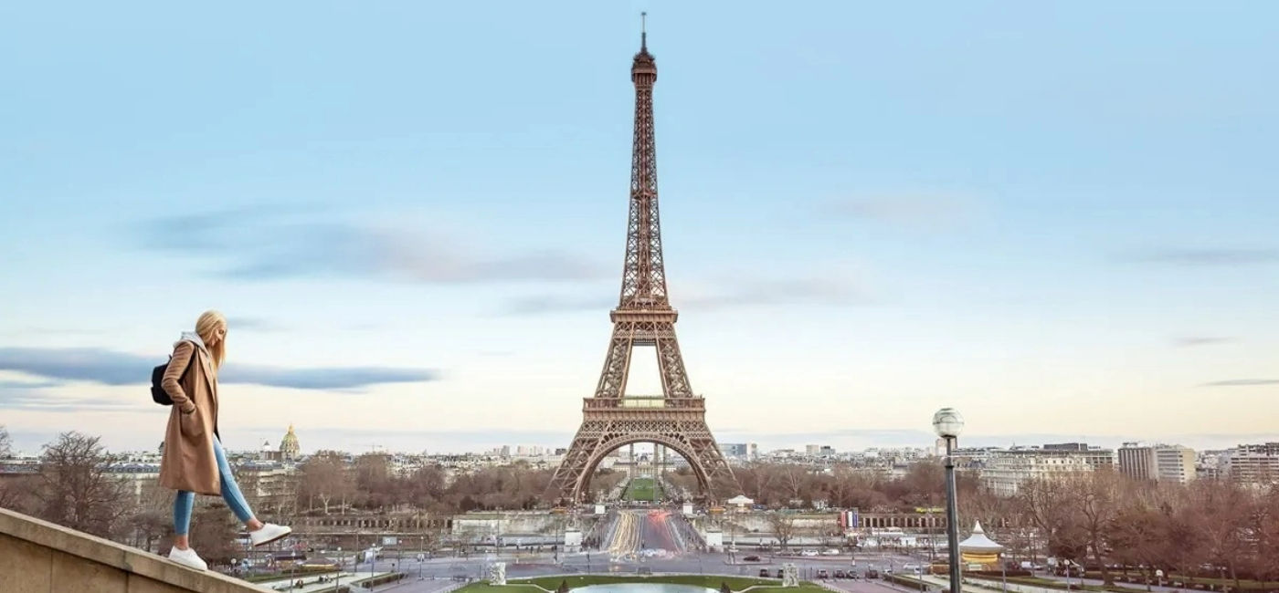 Image: A young woman walks by the Eiffel Tower in Paris. (Photo Credit: Contiki)