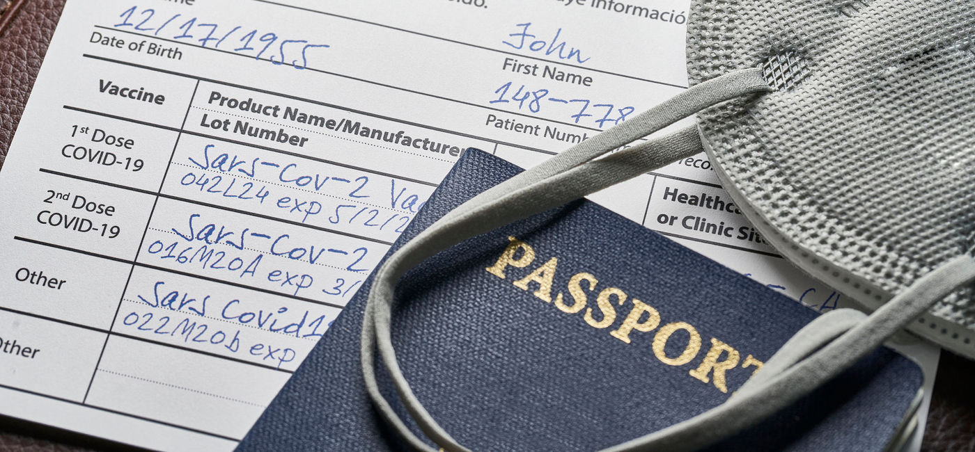 Image: Passport, face mask and a CDC-issued COVID-19 vaccination card with details of initial vaccines and booster shots. (photo via iStock/Getty Images Plus/Bill Oxford)