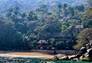 Eco resort on hillside with beach and ocean in foreground