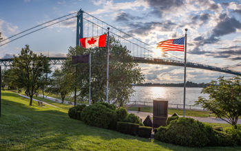 The U.S. and Canadian flags flying in front of the Ambassador Bridge, which links Detroit, Michigan with Windsor, Ontario.