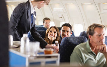 Flight attendant serving water bottles aboard an airplane.