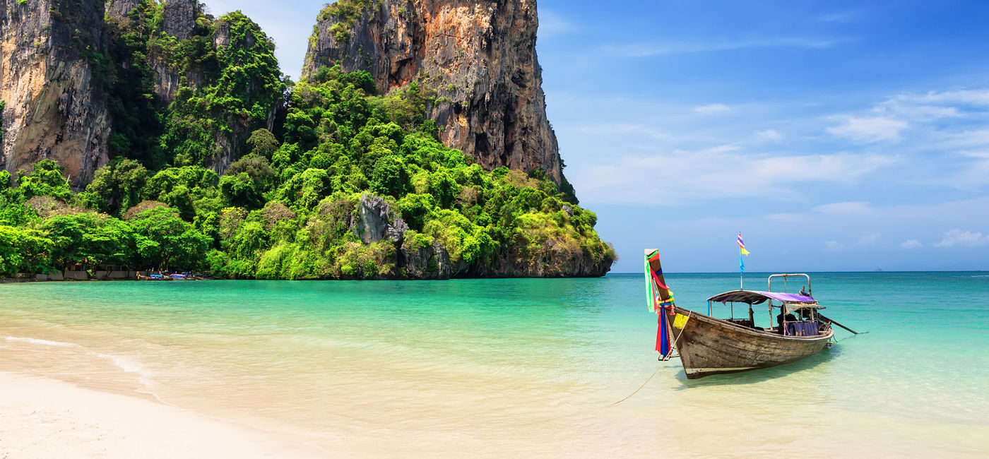 Image: Traditional wooden longtail boat moored on a beach in Thailand. (photo via iStock/Getty Images Plus/Preto_perola)